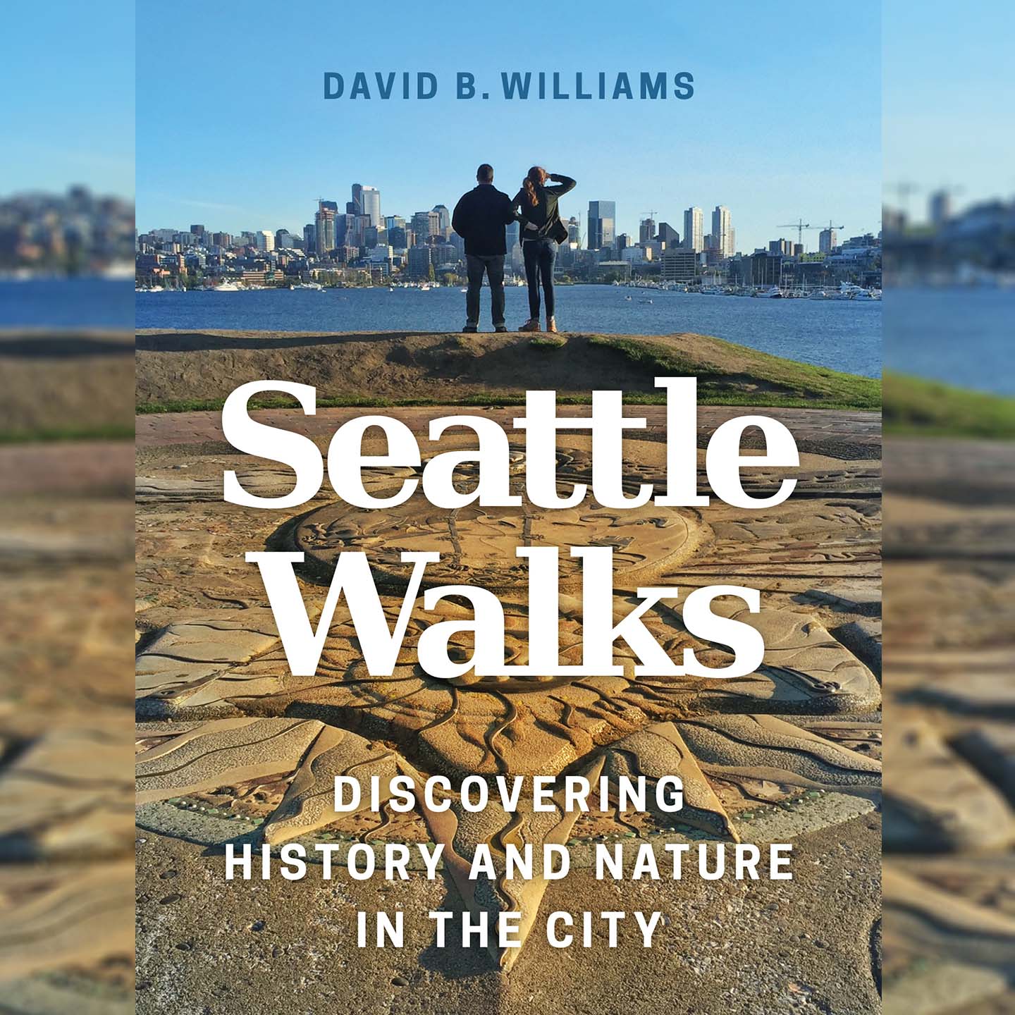 Seattle Walks by David Williams - the book cover features two people standing with their backs to the viewer, looking across the water at the Seattle skyline. In the foreground behind them is concrete ground that has been zhuzhed up with an artistic relief sculpture.