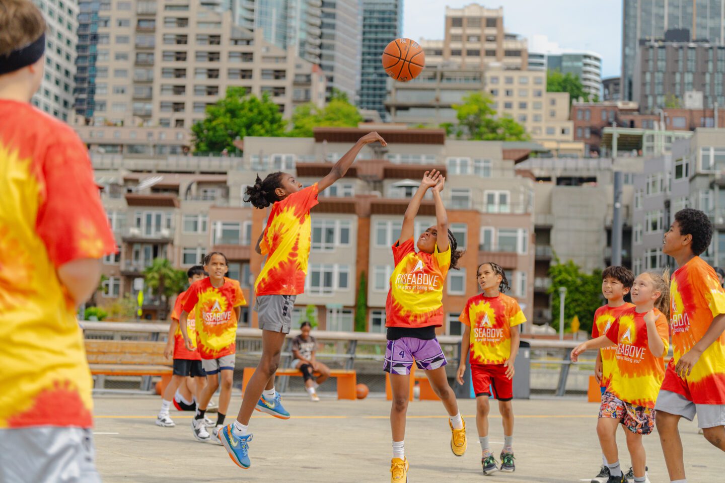 A group of people wearing matching shirts playing basketball.