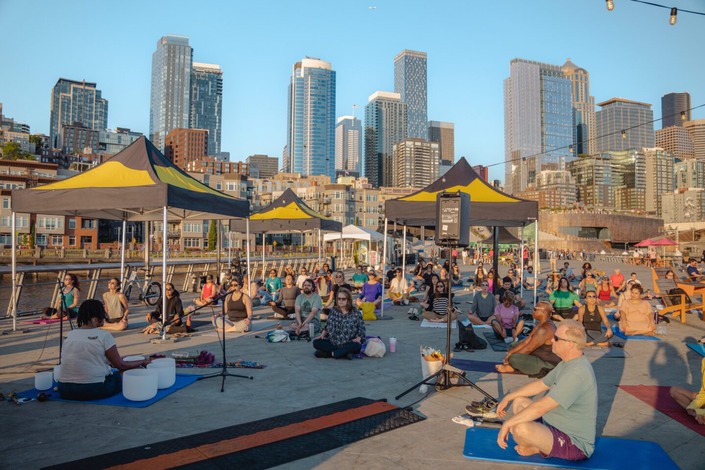 A group of people sitting on the group facing an instructor.