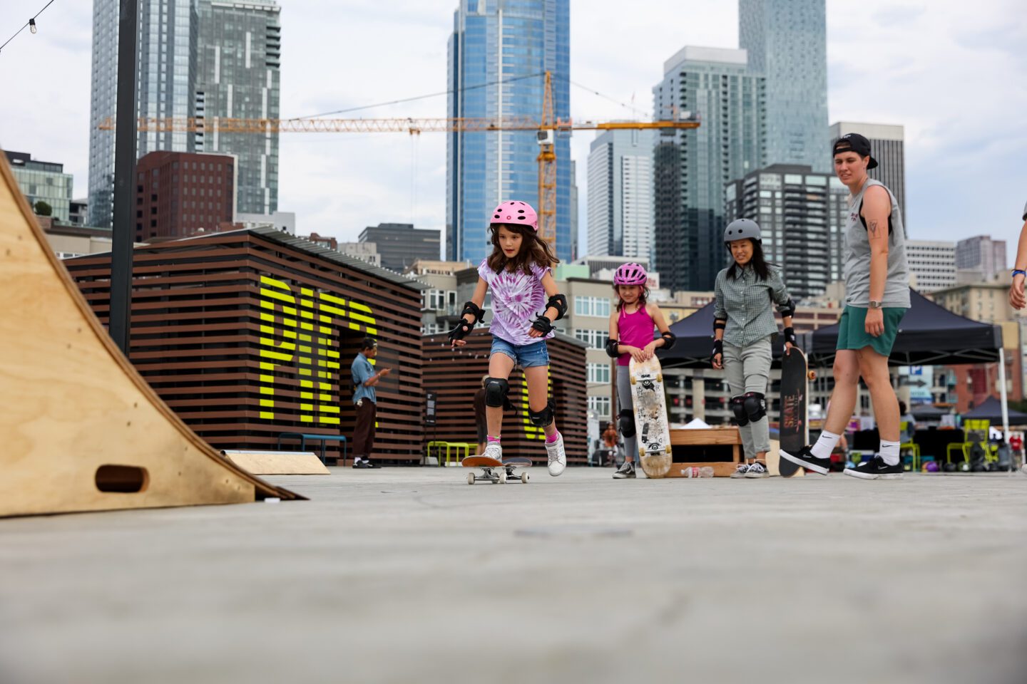 Skate Like a Girl happens select Tuesdays this summer. A girl gets ready to skateboard up a ramp while others look on. 2022 photo by Adam Lu.