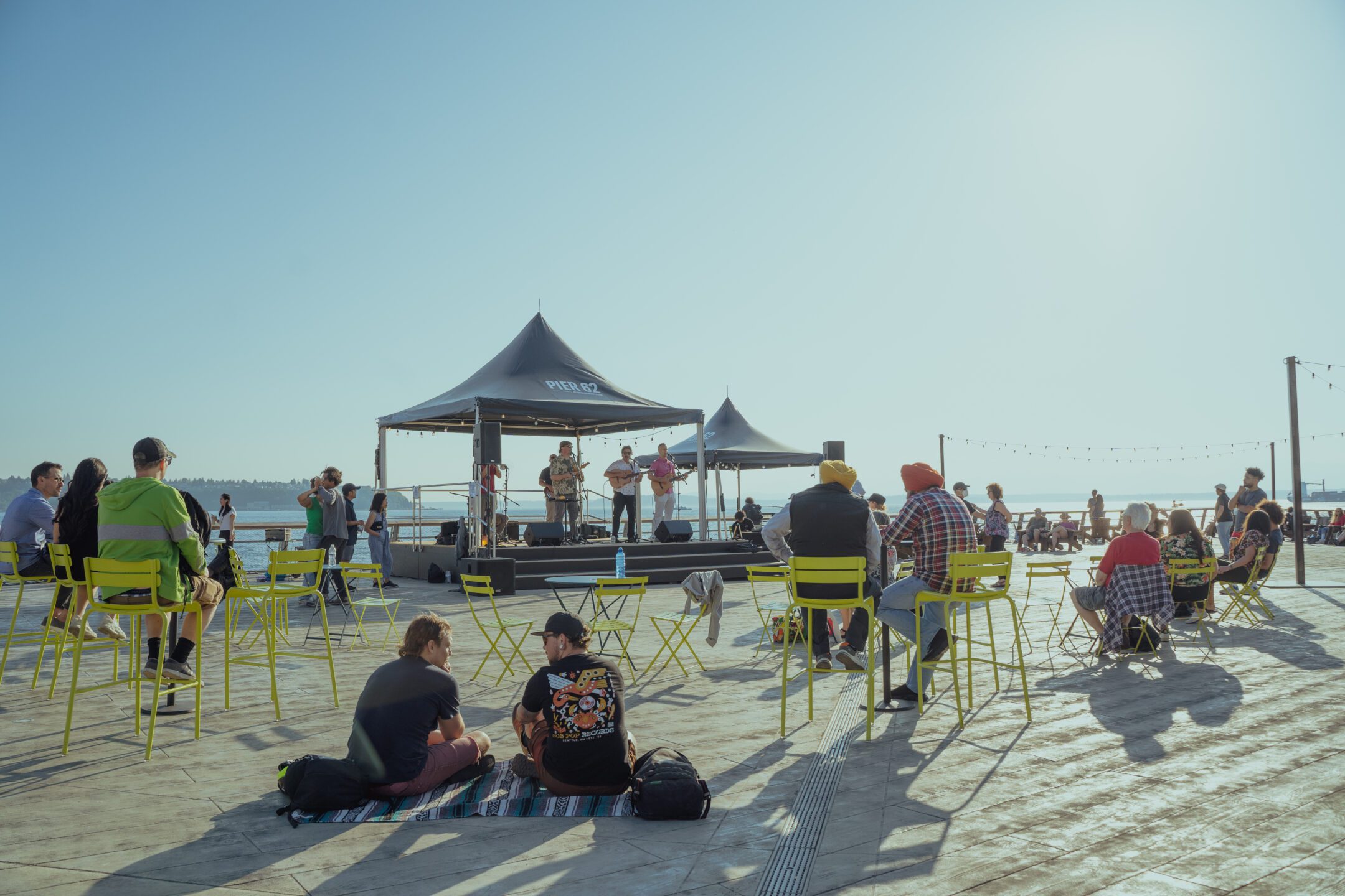 Visitors at Pier 62 enjoy a cloudless summer day at Pier 62 as they sit and watch a performance by Cuban Son group, SuperSones.