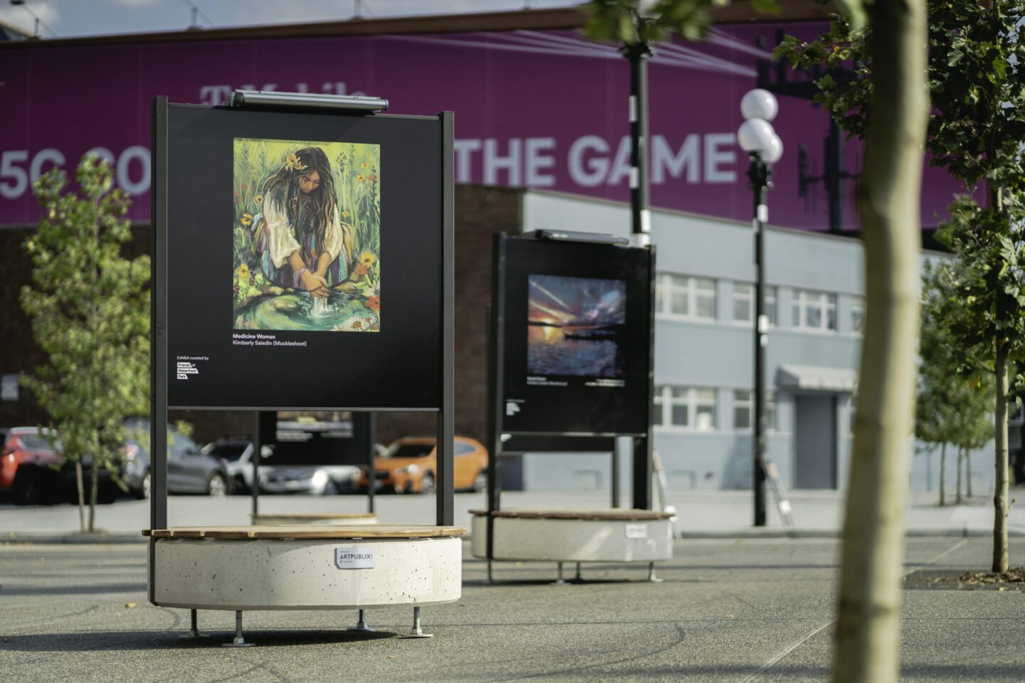 Large art display with colorful artwork in an urban setting with a few trees in the background.