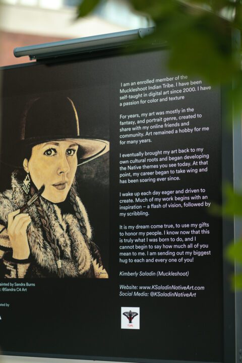 Photo of a large art display with the portrait of a woman in a hat with words to the right describing about the woman.