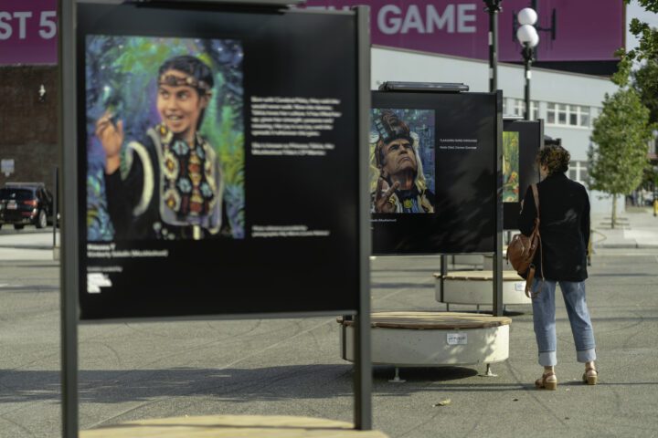 Large metal art displays in a plaza with a visitor looking at one of the displays.