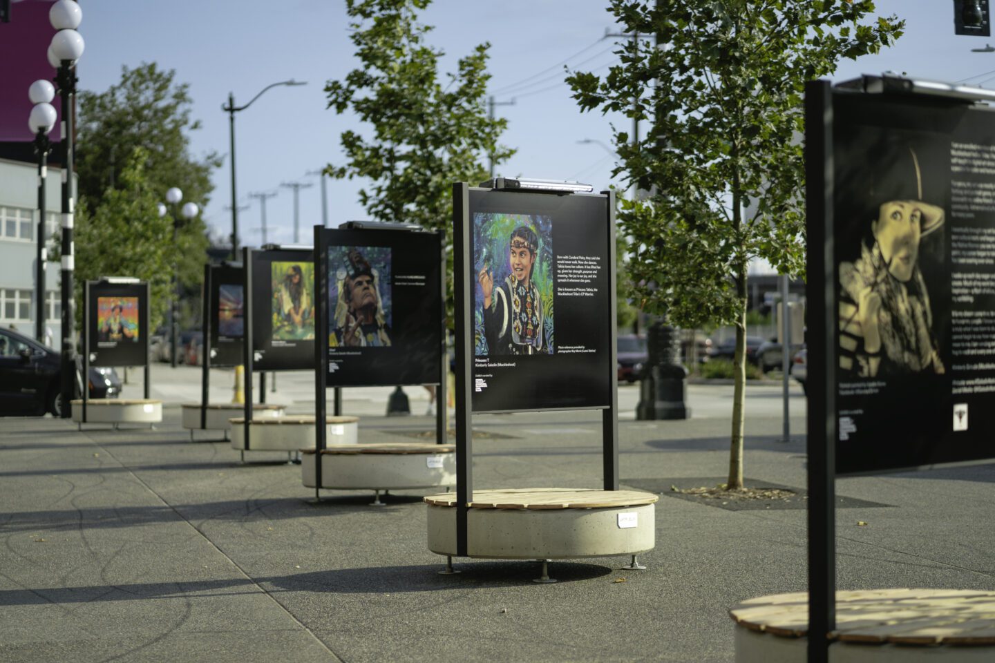 Six large metal art displays in a row along a street and plaza.