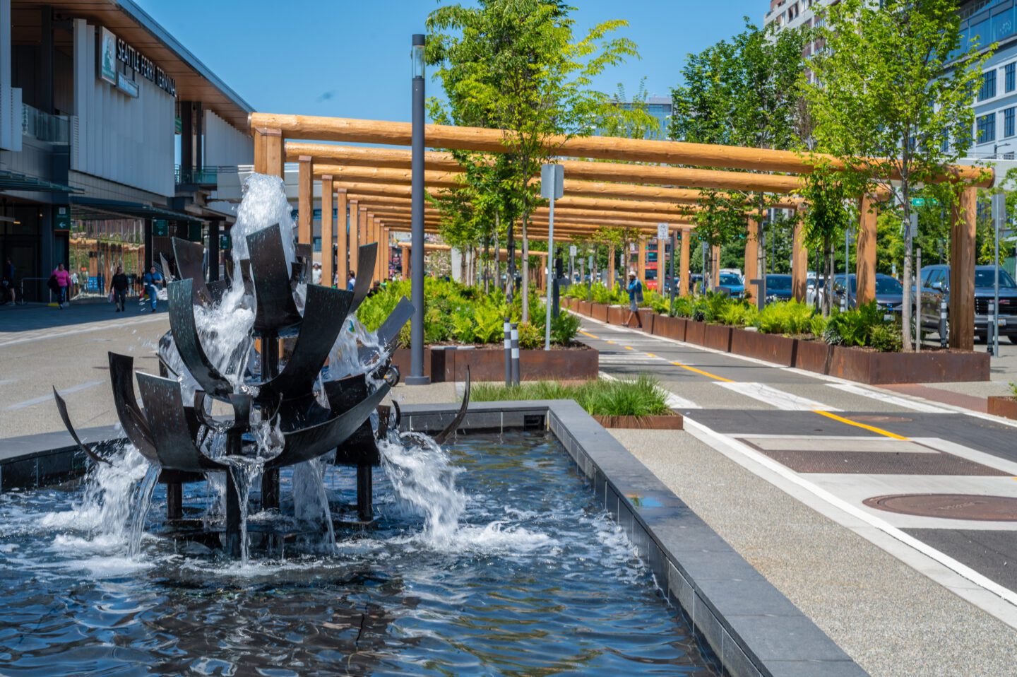 Artistic fountain running with bike path and greenery in background.