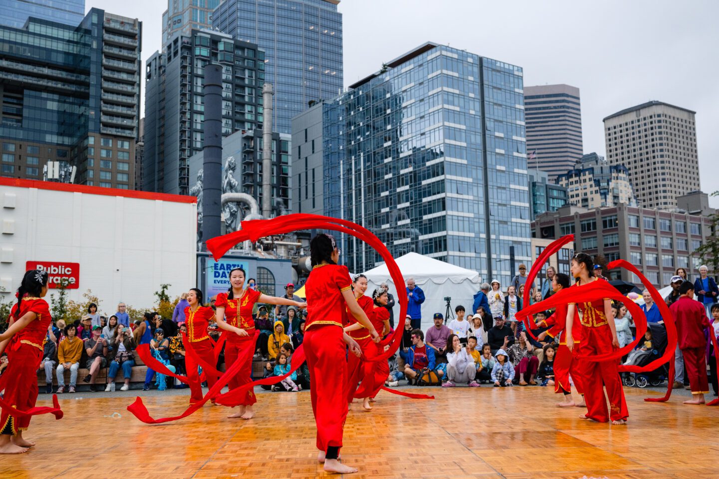 Performers wearing red outfits from Melody Institute swerving ribbons in front of a crowd at Pier 58.