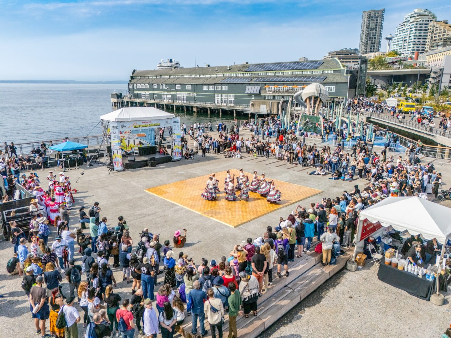 A group is performing on a dance floor in the middle of Pier 58 with spectators on the outside.