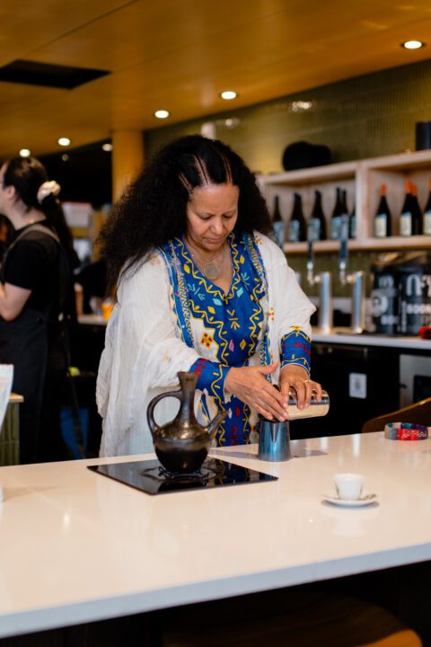 Efrem’s mom, Tsegheweini, prepares a traditional East African coffee ceremony at Overlook Walk Café, honoring a ritual rooted in gathering, pause, and connection.