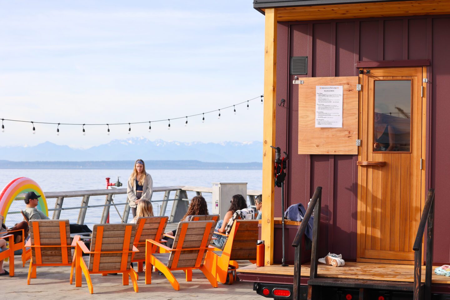 Guests sitting in orange chairs, facing west on Pier 62.