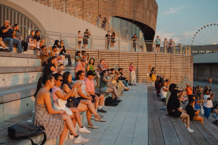 A large group of people sitting on built-in bench seating.
