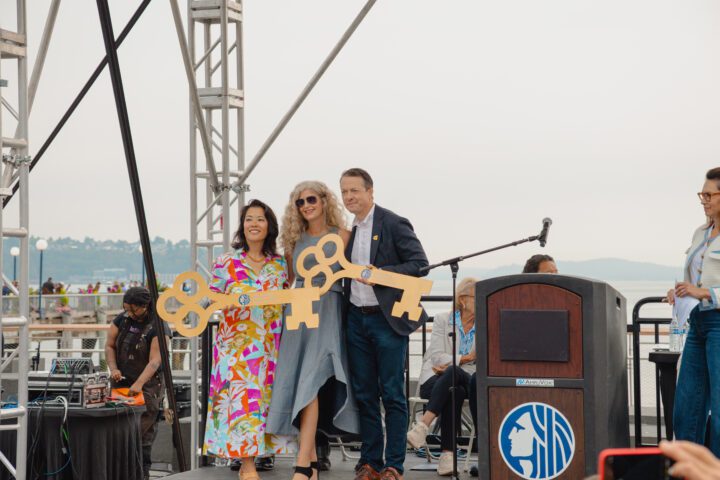 Three individuals on stage holding keys