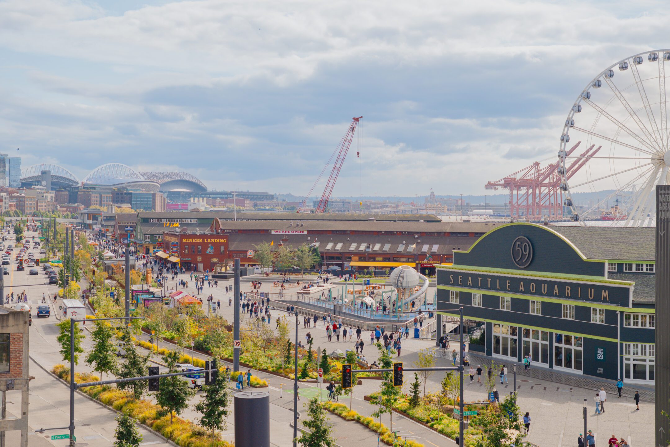 Aerial view of Seattle's waterfront looking south, showing the Park Promenade, Seattle Aquarium, Great Wheel and Lumen Field in the distance