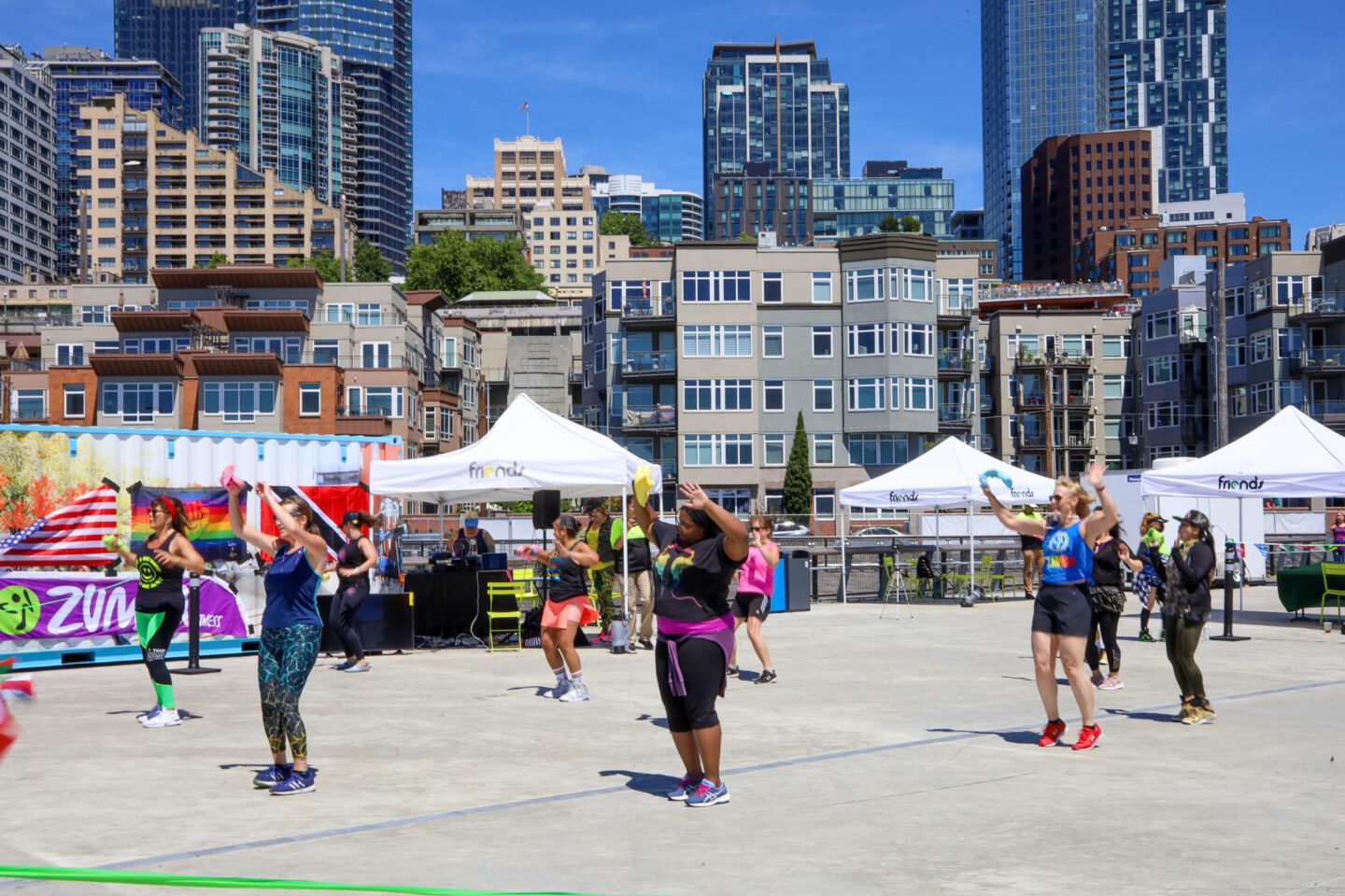 A group of people on a pier surrounded by city buildings.