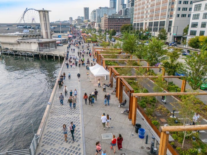 A group of people walking along the Park Promenade on the Seattle waterfront.