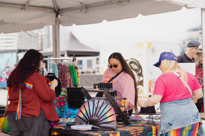 An individual wearing a pink shirt views crafts on a table.