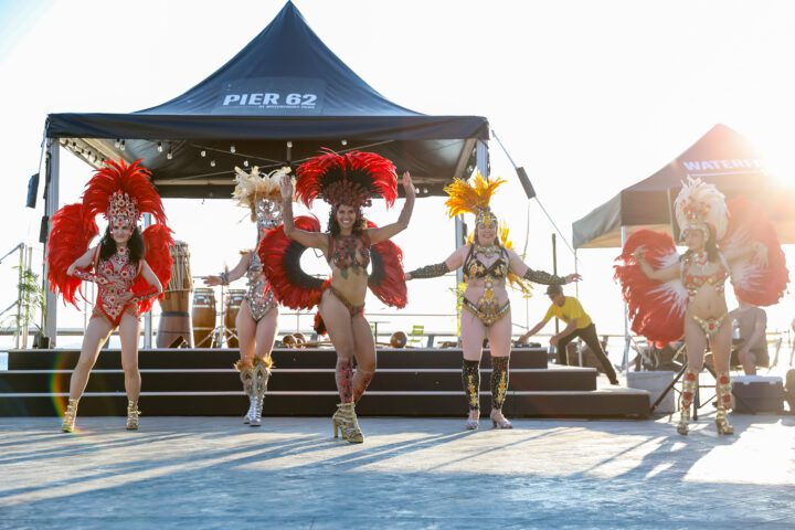 Dancers in feather attire performing in front of a stage.