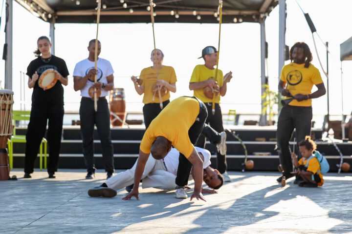 Capoeira group in front of a stage in motion.