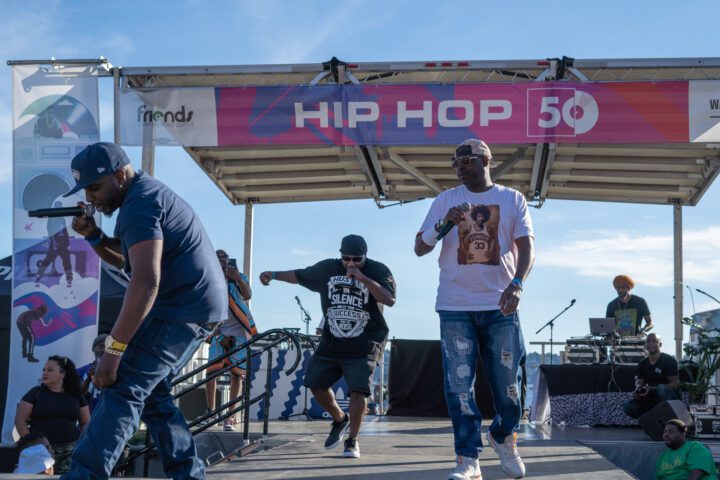 Performers holding microphones on a stage that reads Hip Hop 50.