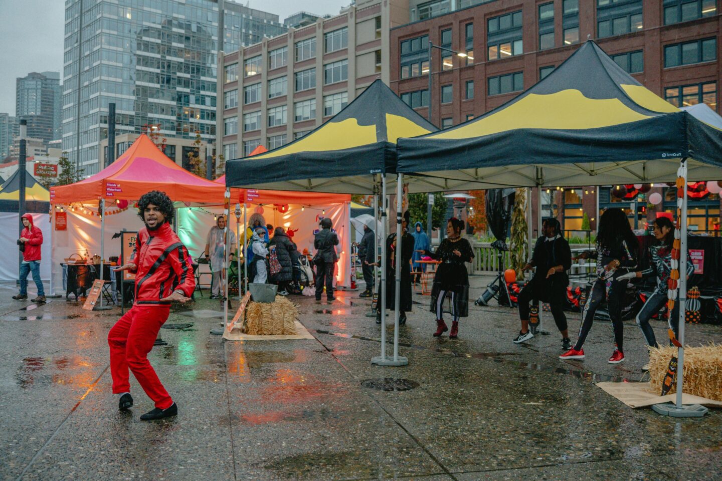 A performer in a red outfit surrounded by branded event tents.