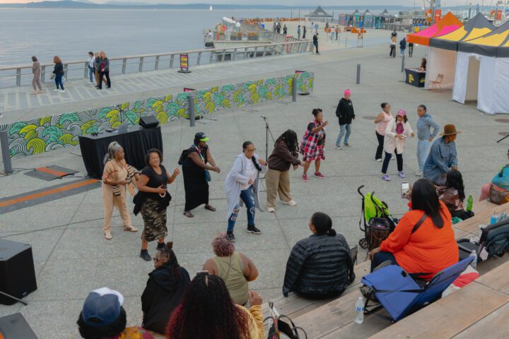 A group of people dancing in front of a crowd sitting on built in seating.