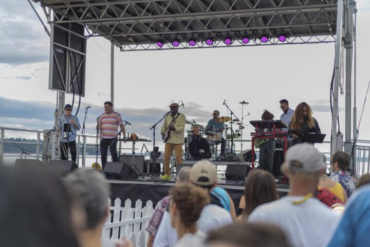 A band performing on a large stage to a crowd of people.