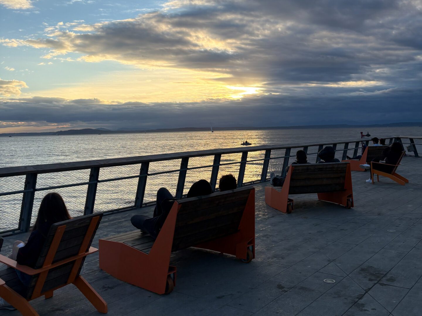 People sitting on a pier watching the sunset.