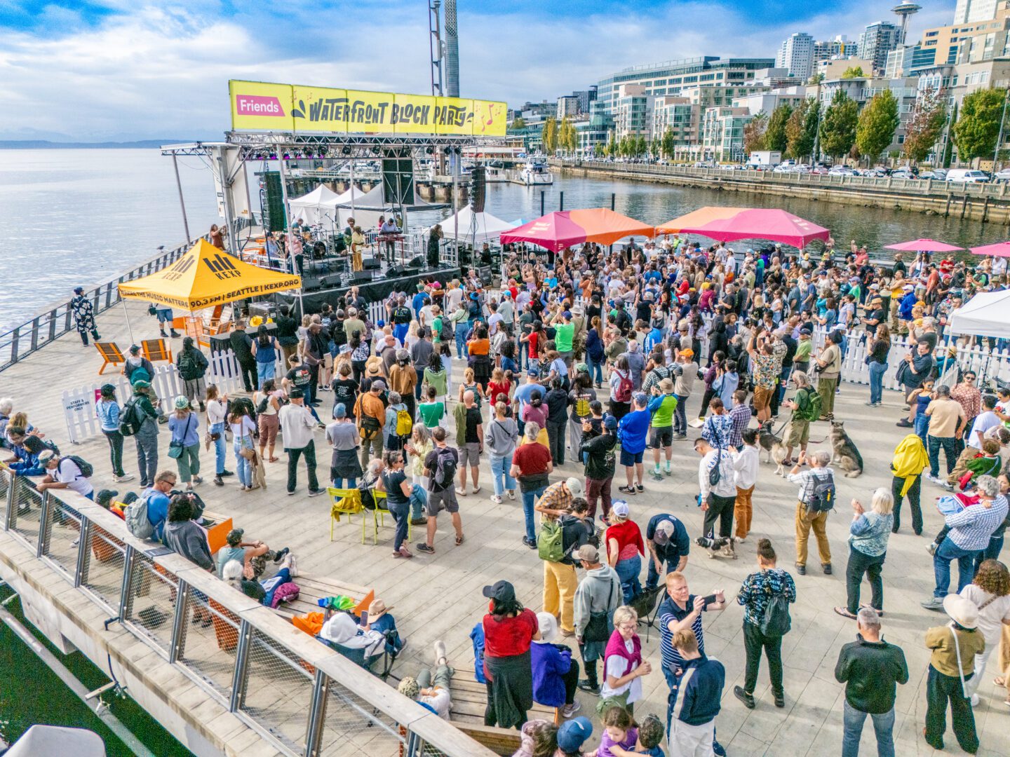 A crowd of people standing in front of a stage with a banner that reads Waterfront Block Party.