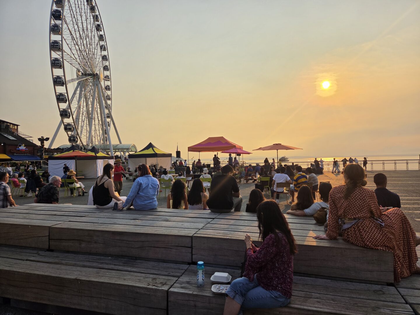 A crowd of people watching a performance at sunset.