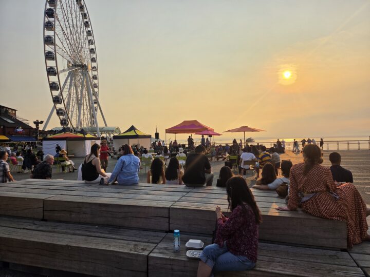 A crowd of people watching a performance at sunset.