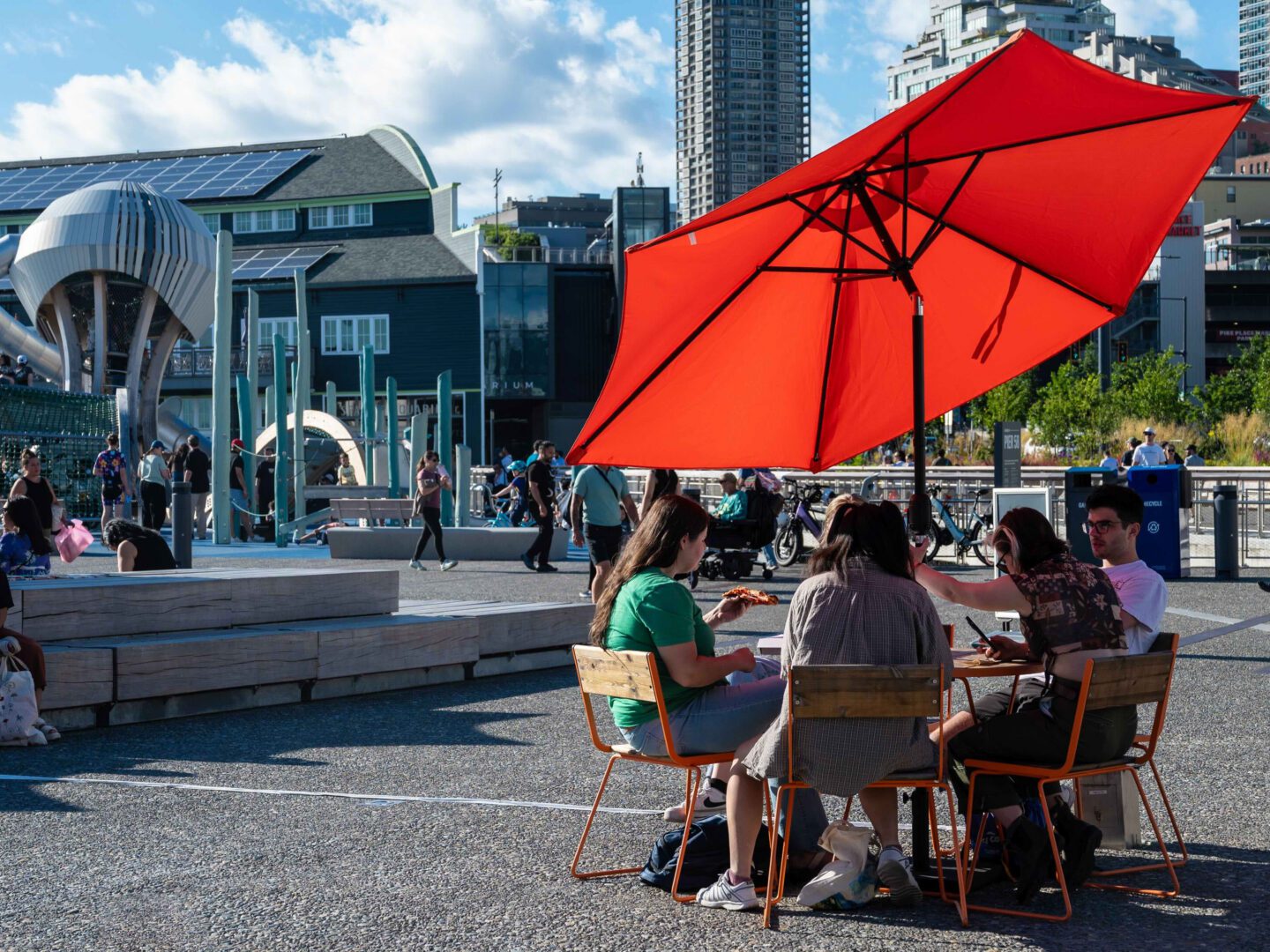 A group of people sitting at a table with a red umbrella.